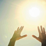 Mixed race womanand#039;s hands reaching toward sun